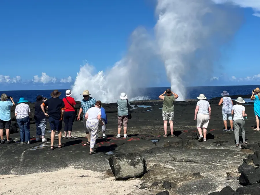Tourists watch ocean blowholes erupt on a rocky coast