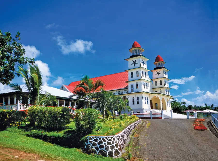 White church with red roofs amid tropical gardens