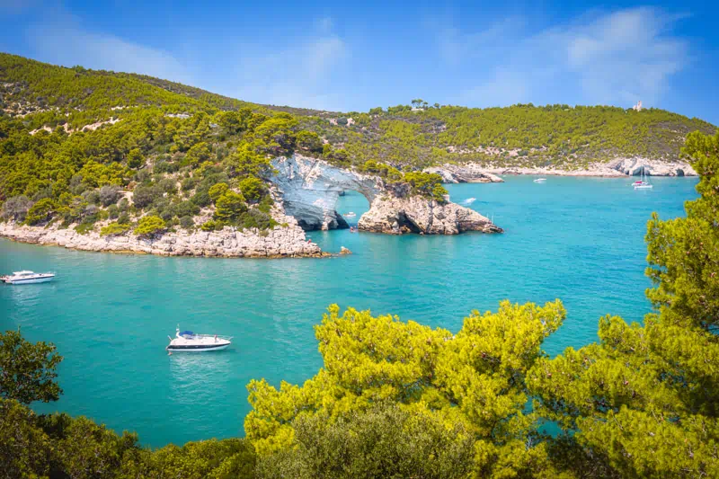Turquoise cove with rocky arch and boats