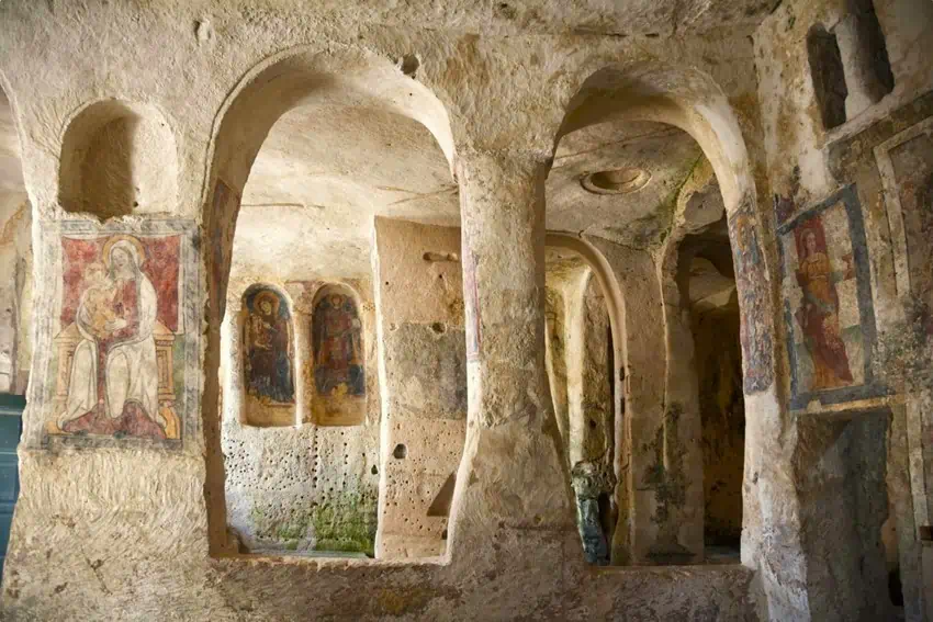 Ancient cave church with faded frescoes and arches