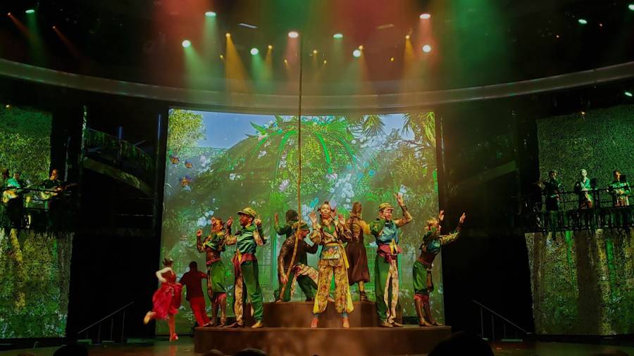 Colourful stage performance with dancers and forest backdrop