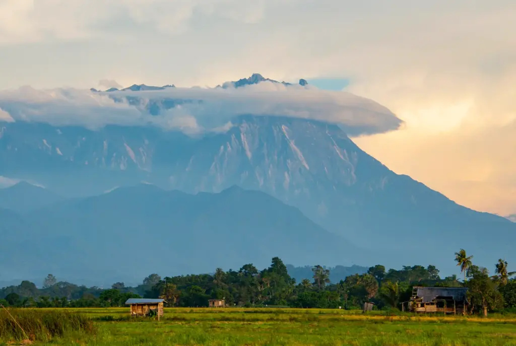 Cloud-capped mountain above rural green fields