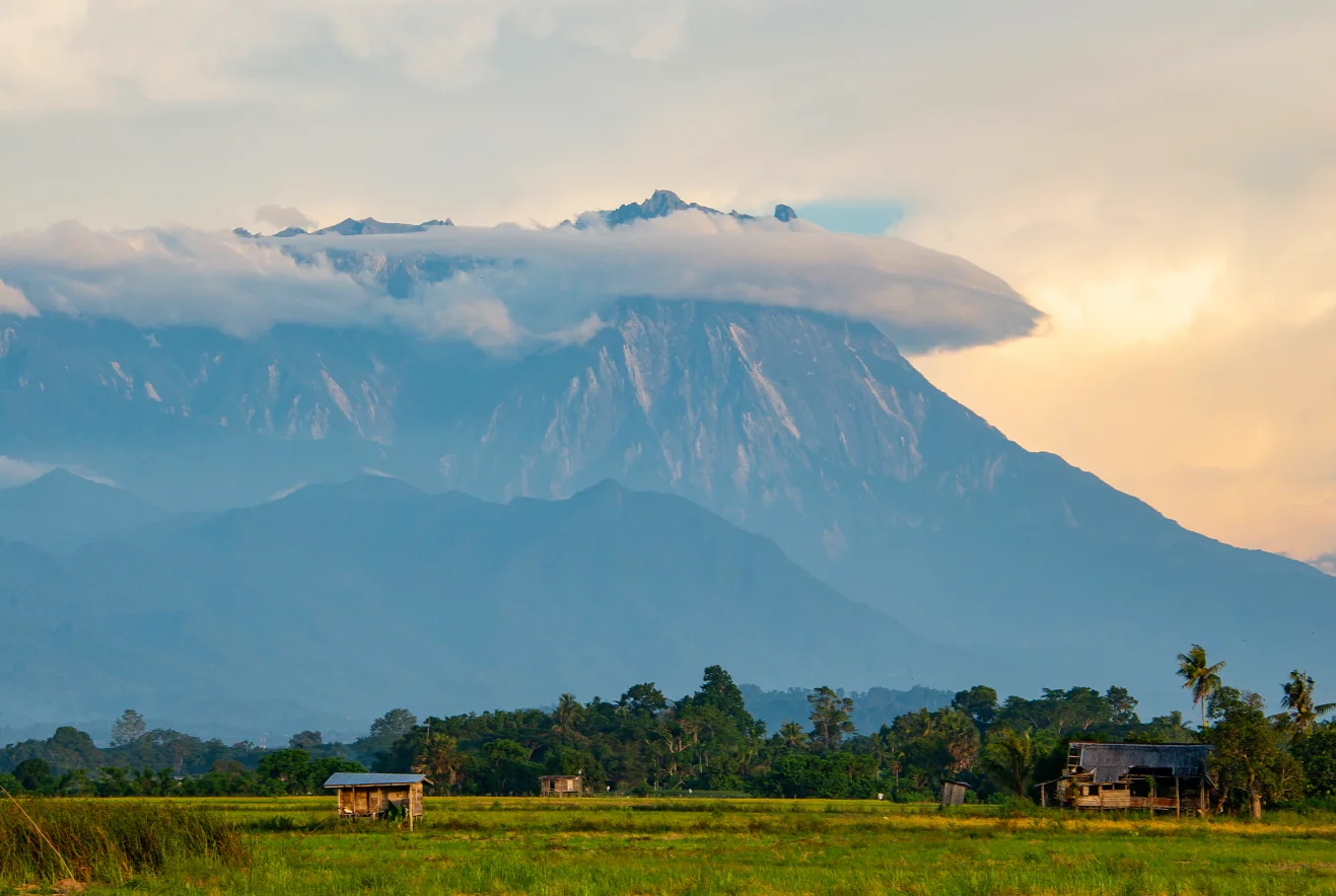 Cloud-capped mountain above rural green fields