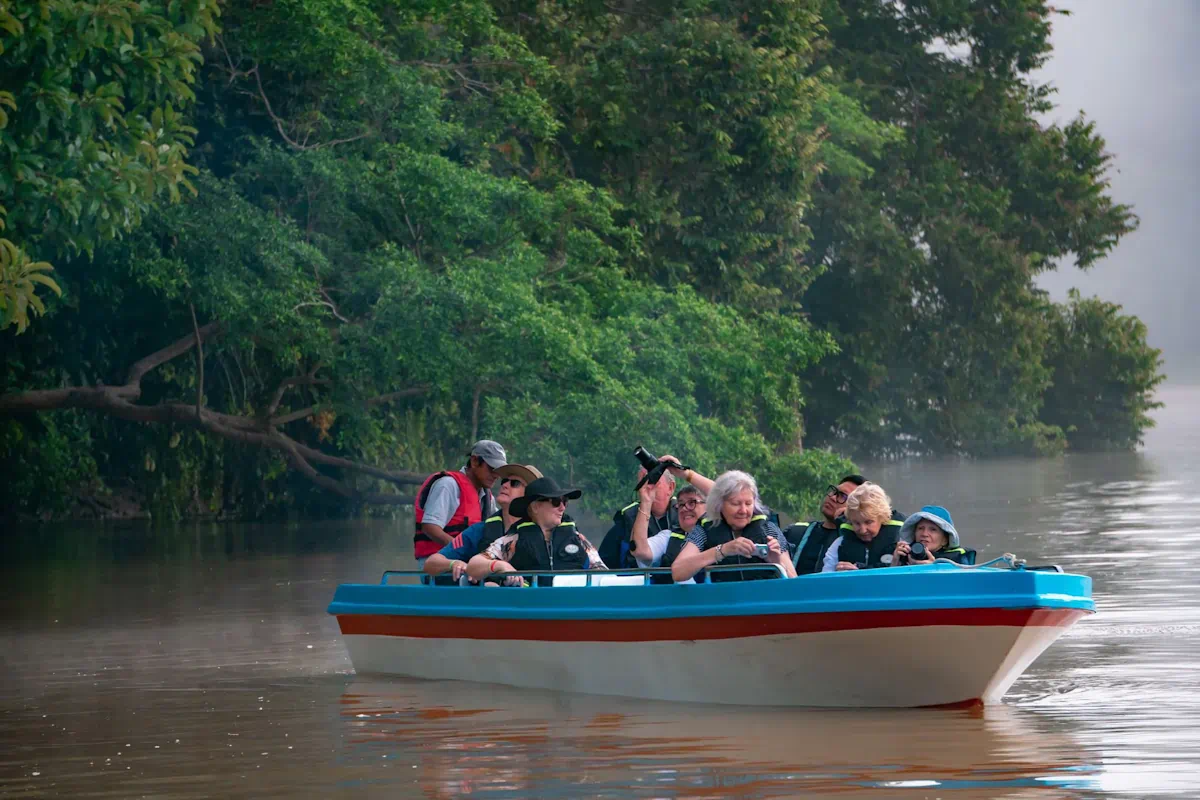 Tourists on small boat exploring lush river
