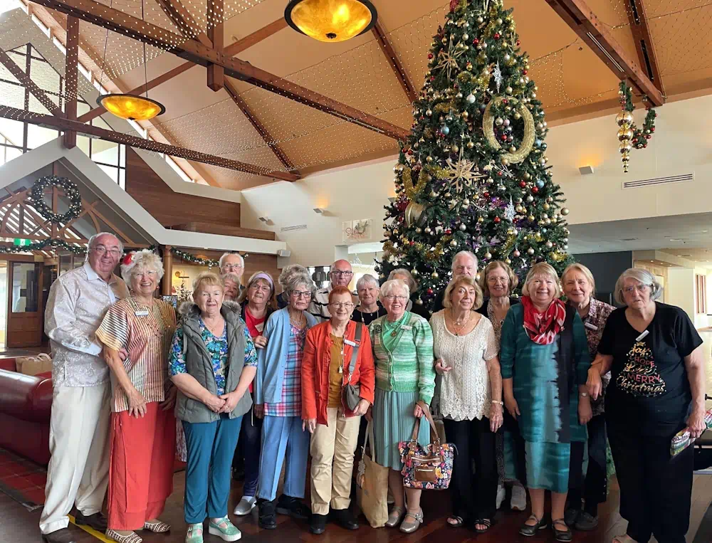 Seniors gathered beside large decorated Christmas tree indoors