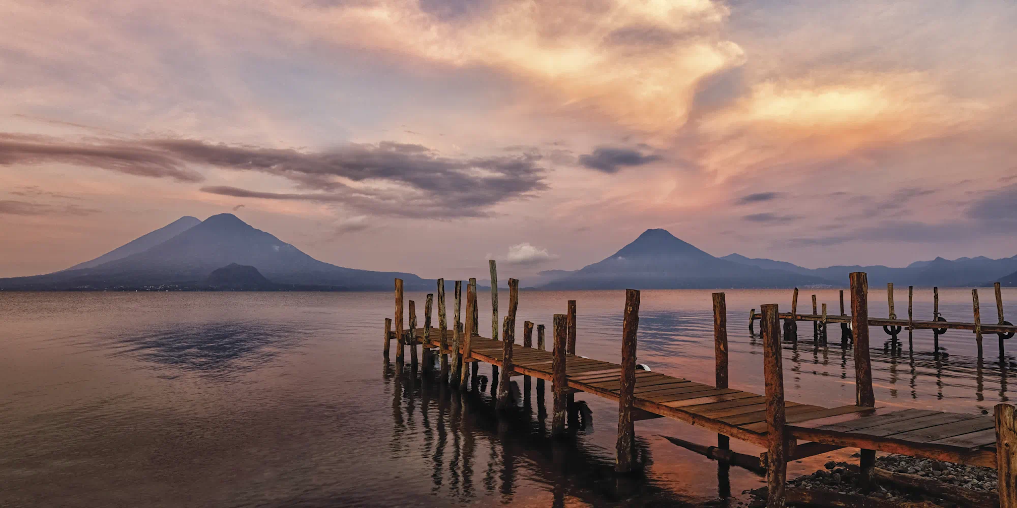Wooden pier on calm lake at sunset