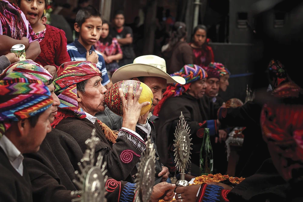 Men in traditional attire drinking from ceremonial gourd