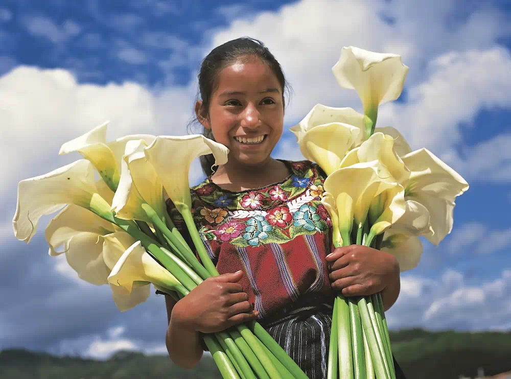 Smiling woman holding white calla lilies outdoors