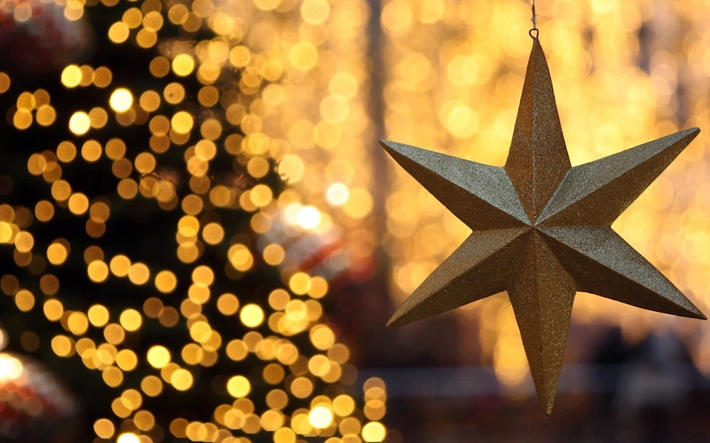 Golden star ornament with festive bokeh lights