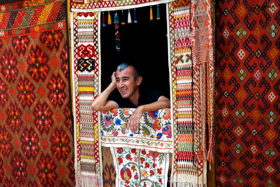 Smiling man framed by colourful patterned woven rugs