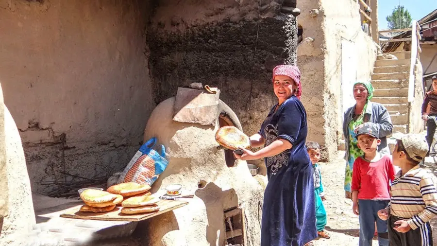 Woman baking flatbread beside a traditional clay oven