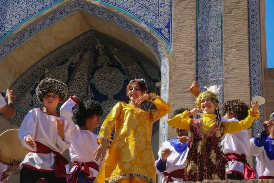 Traditional dancers perform before an ornate tiled Islamic arch