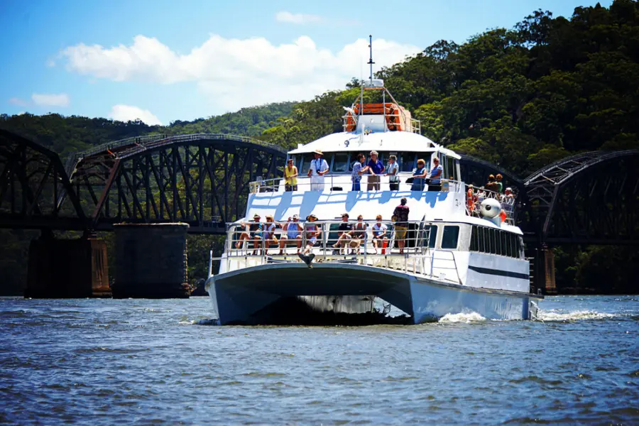 Passenger ferry cruising past a steel bridge
